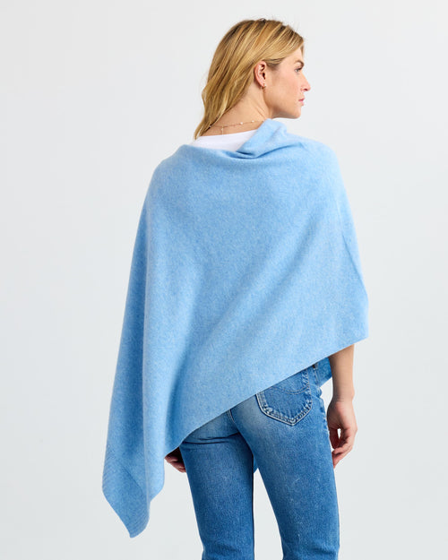 LIFESTYLE / EDITORIAL: Woman wearing light blue cashmere wrap and jeans, viewed from the back against a white background