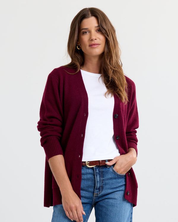 LIFESTYLE / EDITORIAL: Woman wearing cabernet-colored cashmere cardigan over white tee and blue jeans against white
