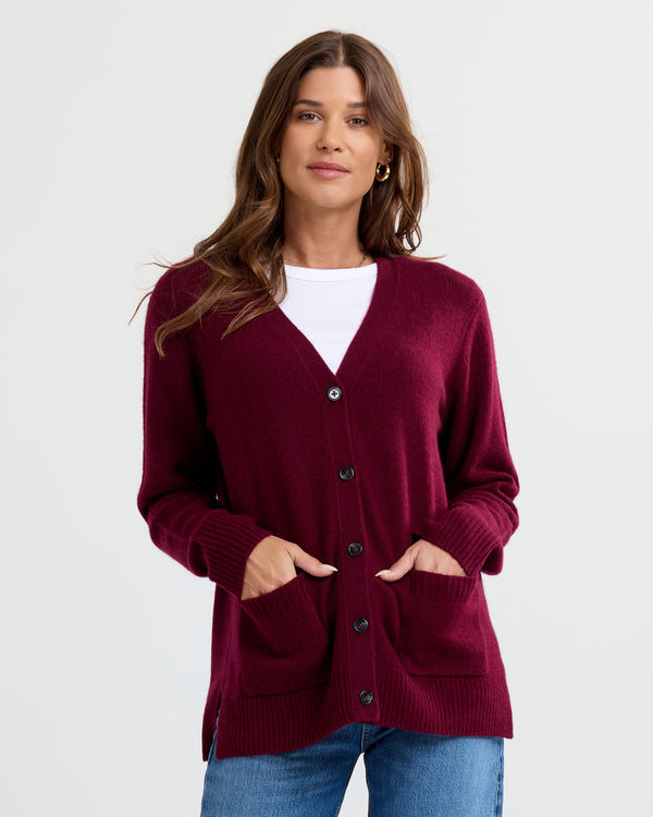 LIFESTYLE / EDITORIAL: Woman wearing a Cabernet-colored cashmere cardigan over white top and blue jeans, hands in pockets