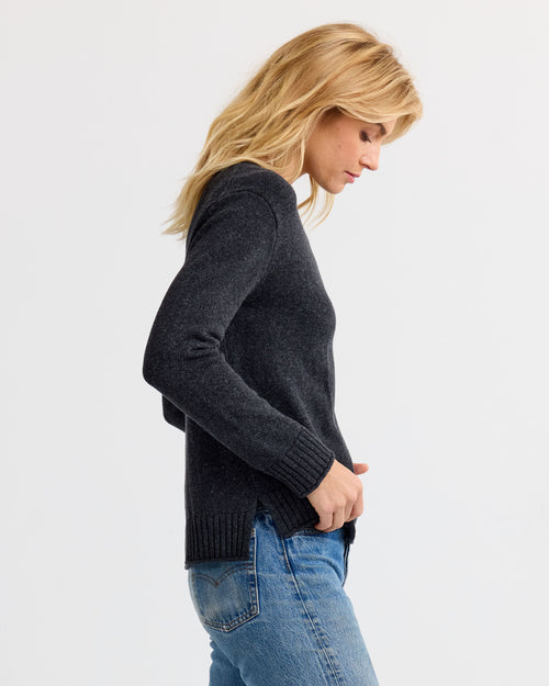 LIFESTYLE / EDITORIAL: Woman in charcoal cashmere sweater and blue jeans, side profile against white background