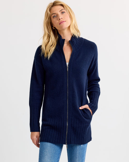 Front view image of a woman wearing a navy zip-up cashmere cardigan with pockets and ribbed cuffs