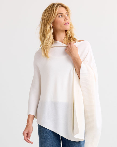 LIFESTYLE / EDITORIAL: Woman wearing ivory cashmere poncho with asymmetrical hem and 3/4 sleeves, looking to side