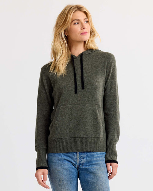 Front view image of a woman wearing a dark olive cashmere hoodie with black drawstrings and blue jeans against white