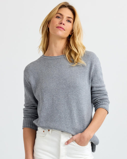 LIFESTYLE / EDITORIAL: Woman wearing light gray cashmere sweater and white pants with hand in pocket against white background