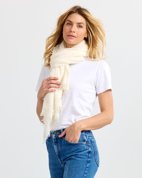 LIFESTYLE / EDITORIAL: Woman wearing white scarf, white t-shirt, and blue jeans against plain background