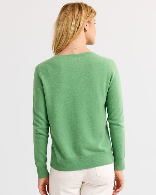 Woman wearing a long-sleeve matcha green cashmere sweater, shown from the back, paired with white pants