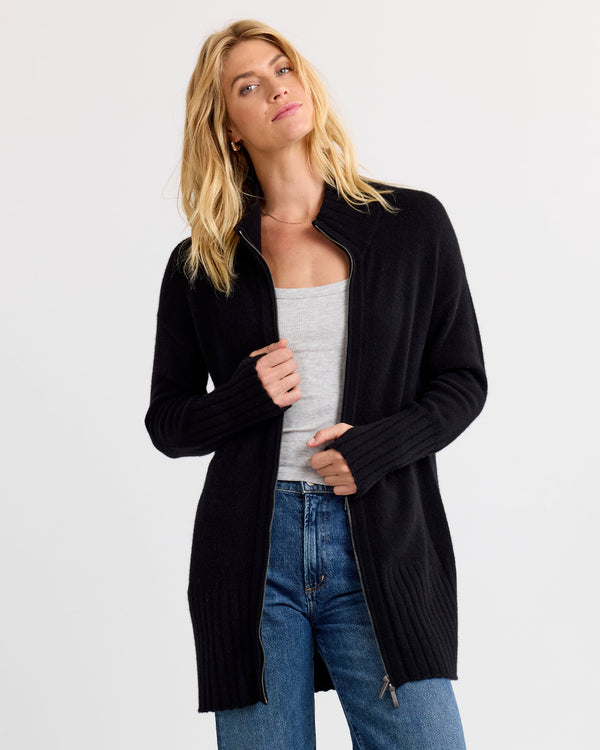 LIFESTYLE / EDITORIAL: Woman wearing black zip-up cashmere cardigan over gray tank and blue jeans against white background