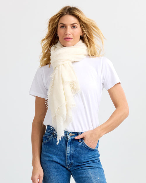 LIFESTYLE / EDITORIAL: Woman wearing white t-shirt, blue jeans, and cream cashmere scarf against white background