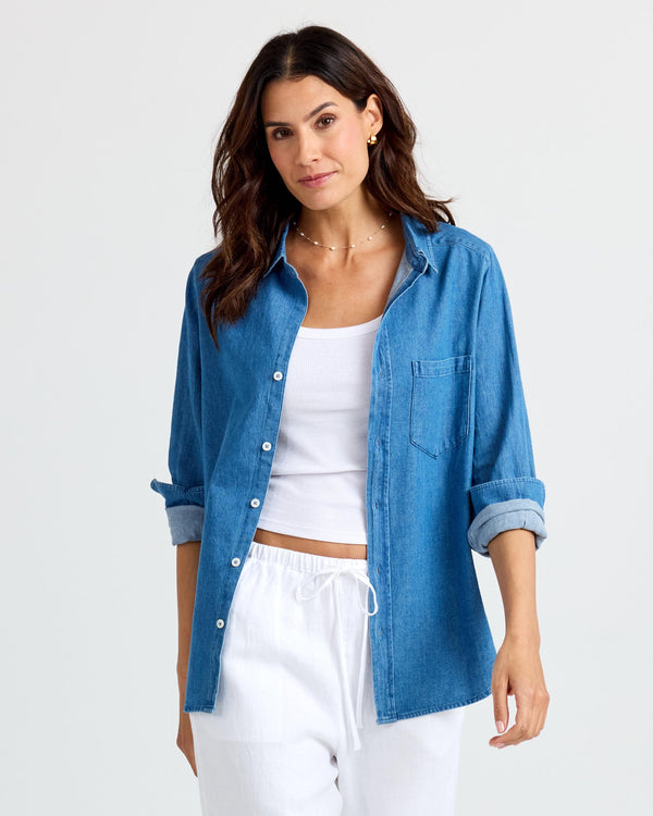 LIFESTYLE / EDITORIAL: Woman wearing medium wash denim shirt over white tank and white drawstring pants against white