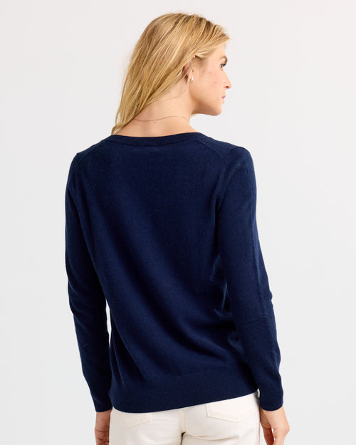 LIFESTYLE / EDITORIAL: Woman with blonde hair wearing navy cashmere sweater, facing away against white background