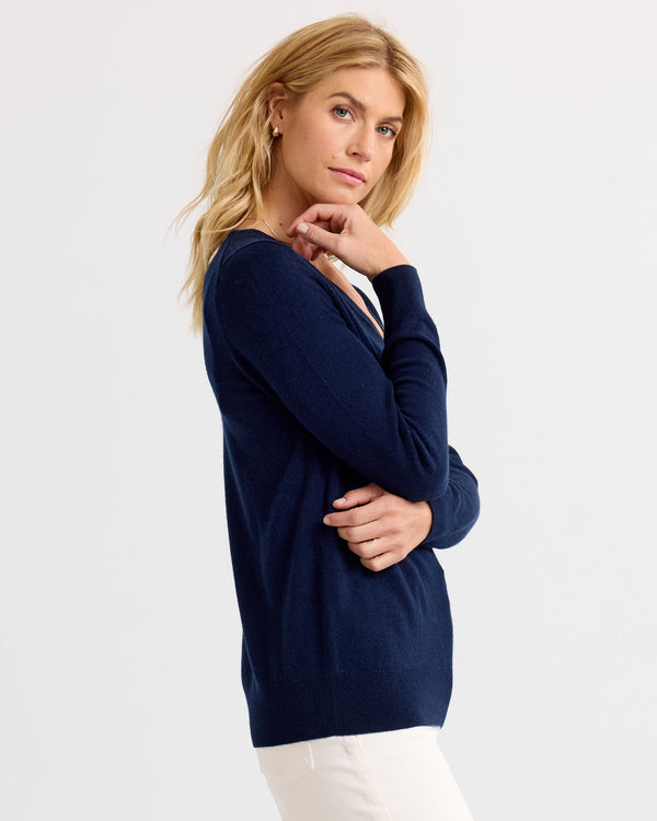 LIFESTYLE / EDITORIAL: Woman in navy cashmere sweater and white pants posing against plain background