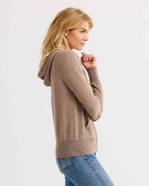 LIFESTYLE / EDITORIAL: Woman in driftwood-colored cashmere hoodie and blue jeans, side profile against white background