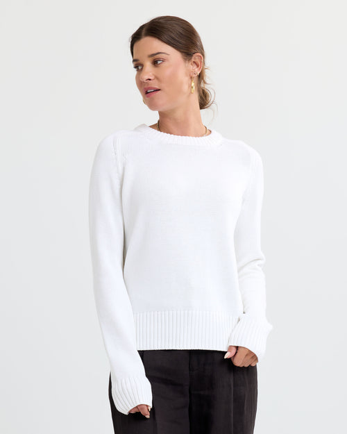 LIFESTYLE / EDITORIAL: Woman wearing cream cashmere sweater with long sleeves and ribbed cuffs, looking sideways