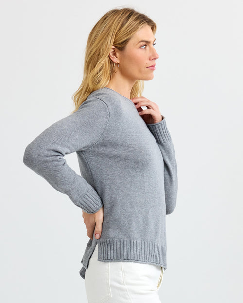 Woman in grey cashmere sweater and white pants, side profile, plain background, filename PURA SU26 CT010A Stone