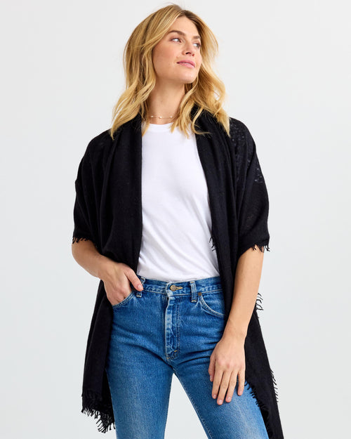 LIFESTYLE / EDITORIAL: Woman wearing black cashmere shawl over white t-shirt and blue jeans against white background