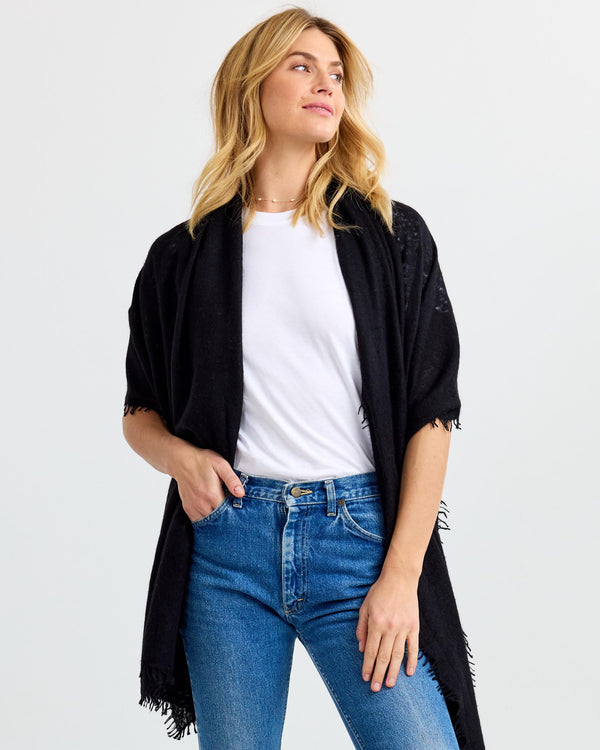 LIFESTYLE / EDITORIAL: Woman wearing black cashmere shawl over white t-shirt and blue jeans against white background