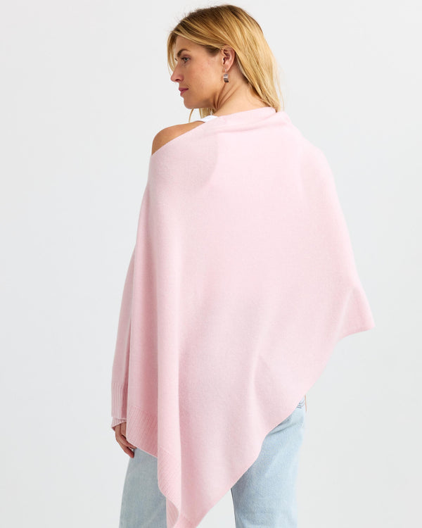 LIFESTYLE / EDITORIAL: Woman wearing blush pink cashmere poncho, viewed from back, paired with light blue jeans
