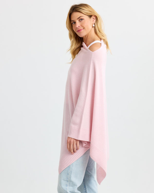 LIFESTYLE / EDITORIAL: Woman wearing blush pink asymmetrical cashmere poncho with cold shoulder detail and light jeans