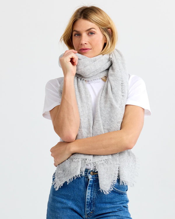 LIFESTYLE / EDITORIAL: Woman wearing light gray cashmere scarf, white t-shirt, and blue jeans against white background