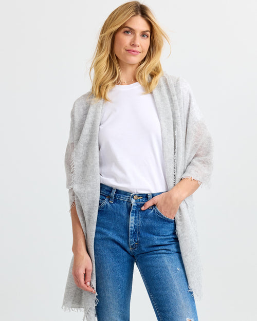 LIFESTYLE / EDITORIAL: Woman wearing light gray cashmere shawl over white t-shirt and blue jeans against white background