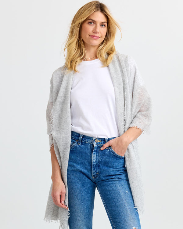 LIFESTYLE / EDITORIAL: Woman wearing light gray cashmere shawl over white t-shirt and blue jeans against white background