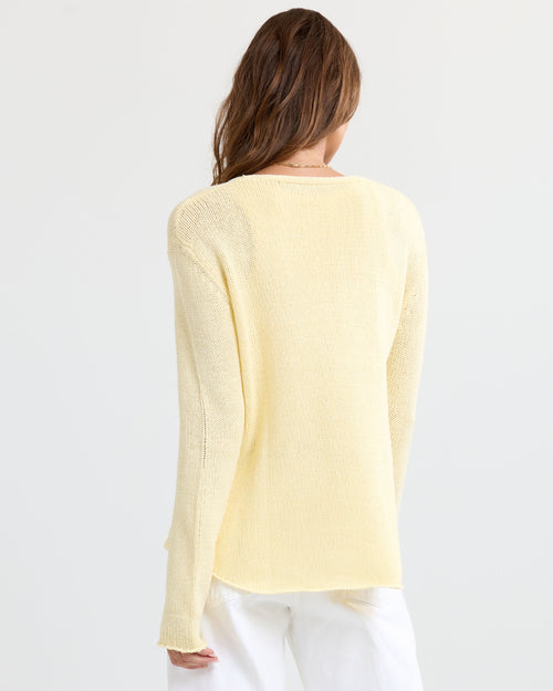 LIFESTYLE / EDITORIAL: Woman wearing a buttermilk yellow cashmere sweater and white pants, shown from the back