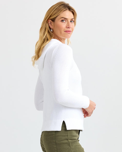 LIFESTYLE / EDITORIAL: Woman in white ribbed cashmere hoodie and olive pants, side view on white background