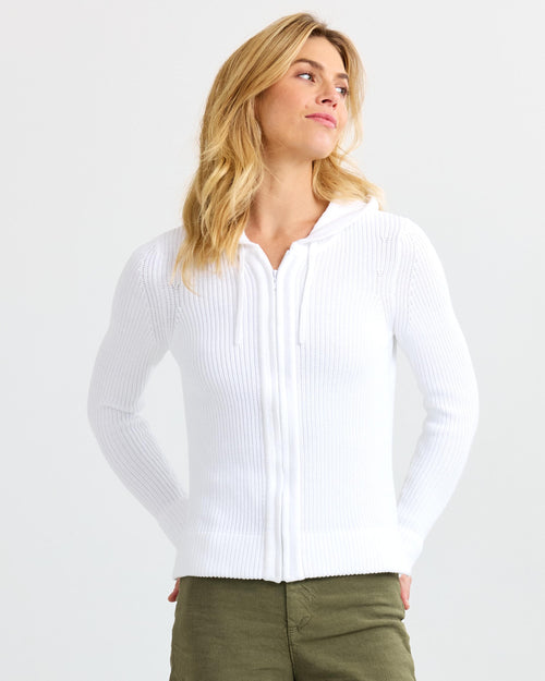 Front view image of a woman wearing a white ribbed zip-up cashmere hoodie with hands behind her back