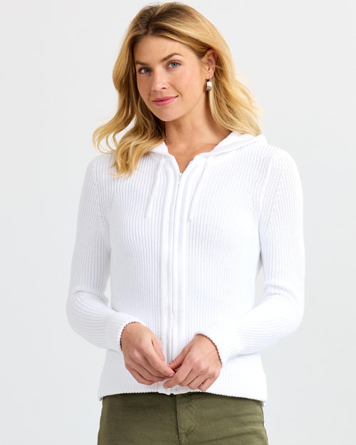 Front view image of a woman wearing a white ribbed zip-up cashmere hoodie with hood down and olive pants