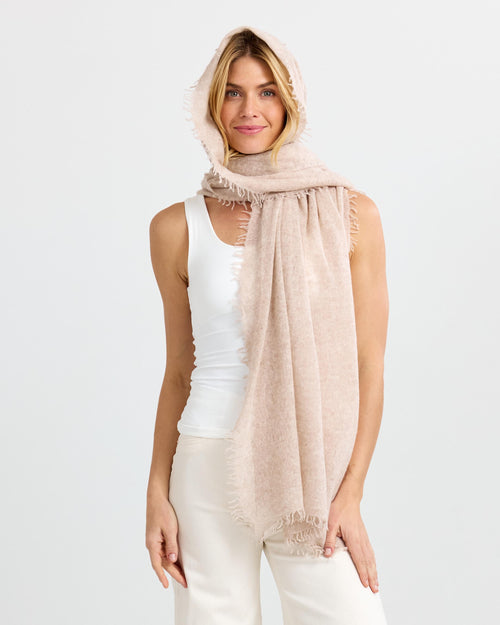 LIFESTYLE / EDITORIAL: Woman wearing a beige cashmere scarf over her head and shoulders with a white tank top and pants