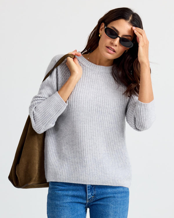 LIFESTYLE / EDITORIAL: Woman wearing gray ribbed cashmere sweater, blue jeans, sunglasses, carrying brown suede bag