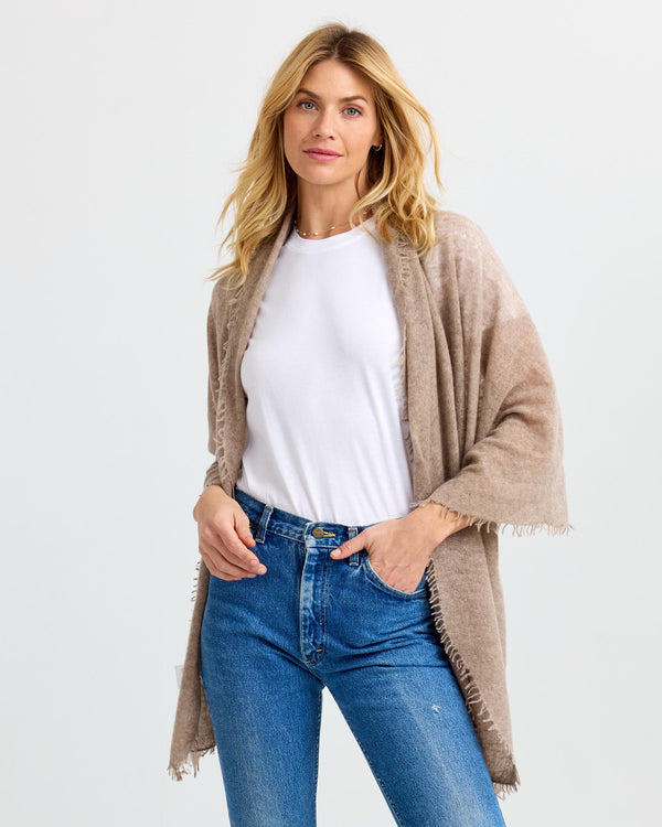 LIFESTYLE / EDITORIAL: Woman wearing beige cashmere shawl over white top and blue jeans against white background
