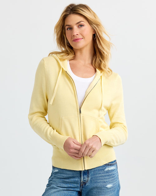 LIFESTYLE / EDITORIAL: Woman wearing a buttermilk yellow zip-up cashmere hoodie over white top and blue jeans