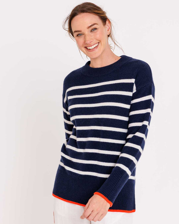 LIFESTYLE / EDITORIAL: Woman smiling wearing navy and ivory striped cashmere crewneck sweater with orange trim
