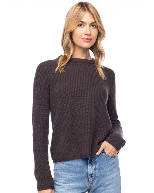 LIFESTYLE / EDITORIAL: Woman wearing dark chocolate ribbed cashmere crewneck sweater and light blue jeans, hand in pocket