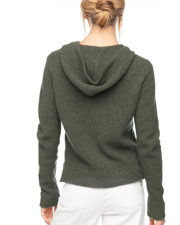 LIFESTYLE / EDITORIAL: Woman wearing dark olive cashmere hoodie, back view, paired with white pants against white background