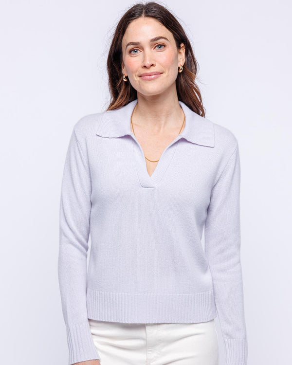 LIFESTYLE / EDITORIAL: Woman wearing lilac cashmere polo crew sweater with collar and white pants against white background