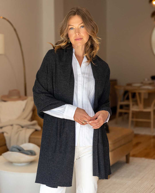 LIFESTYLE / EDITORIAL: Woman indoors wearing charcoal cashmere travel wrap over white shirt and light pants