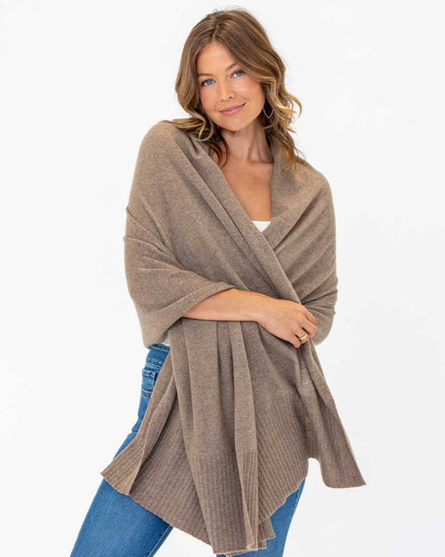 LIFESTYLE / EDITORIAL: Woman wearing a driftwood-colored cashmere travel wrap over casual outfit against white background