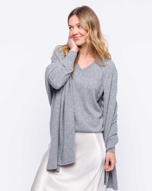 LIFESTYLE / EDITORIAL: Woman wearing grey cashmere wrap and sweater with white skirt against white background