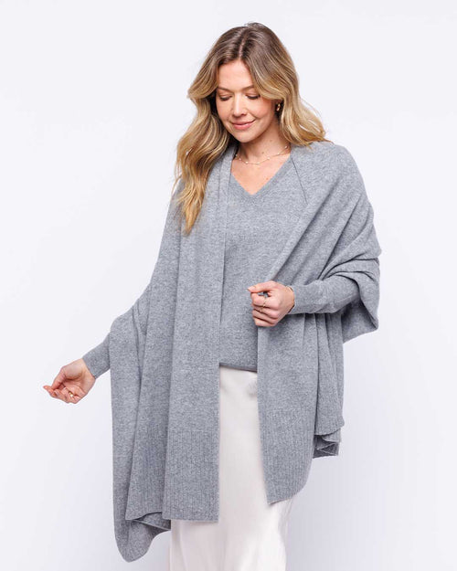LIFESTYLE / EDITORIAL: Woman wearing a light gray cashmere wrap and sweater with white skirt against white background
