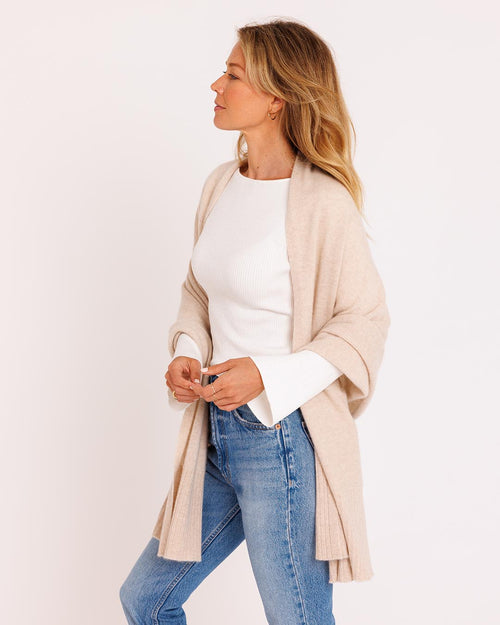 LIFESTYLE / EDITORIAL: Woman wearing oatmeal cashmere wrap over white top and jeans, standing against white background