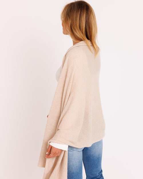 LIFESTYLE / EDITORIAL: Woman wearing oatmeal cashmere wrap and jeans, standing sideways against white background