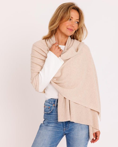 LIFESTYLE / EDITORIAL: Woman wearing oatmeal cashmere wrap over white top and blue jeans against white background
