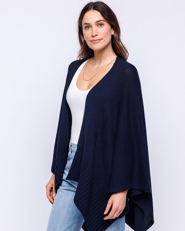 LIFESTYLE / EDITORIAL: Woman wearing navy cotton serape over white tank top and light blue jeans against white background