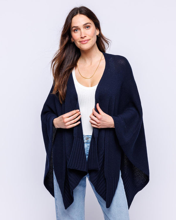 LIFESTYLE / EDITORIAL: Woman wearing navy cotton serape over white top and light blue jeans against white background