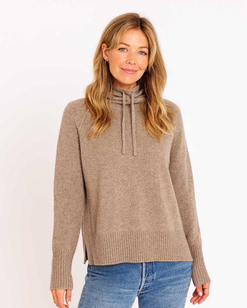 LIFESTYLE / EDITORIAL: Woman wearing a driftwood-colored drawstring funnel neck cashmere sweater and blue jeans against
