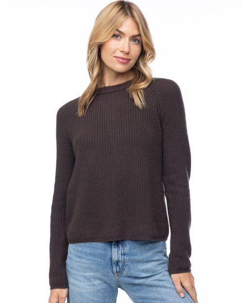 Front-facing image of a woman wearing a dark chocolate ribbed cashmere sweater with blue jeans against white background