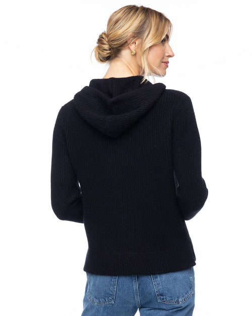 LIFESTYLE / EDITORIAL: Woman wearing black cashmere fisherman hoodie, back view, with hair in a low bun and blue jeans
