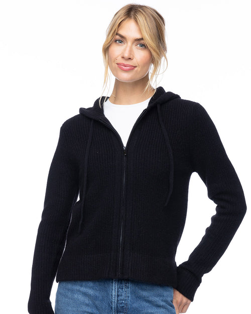 LIFESTYLE / EDITORIAL: Woman wearing black zip-up cashmere hoodie with hood and drawstrings, paired with blue jeans